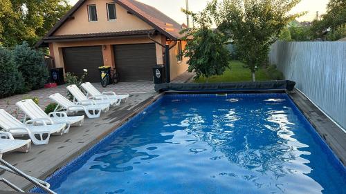 a swimming pool with white chairs and a house at Vila Ovi Salin in Turda