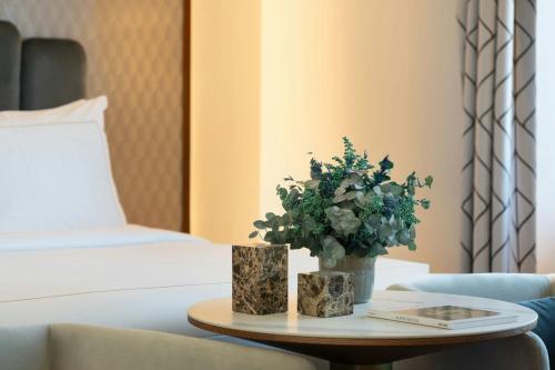 a room with a bed and a table with a plant at Grand Hotel Centenari, Valencia, Autograph Collection in Valencia