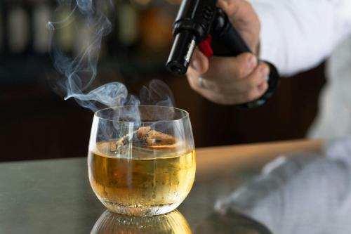 a person is stirring a drink in a glass at Grand Hotel Centenari, Valencia, Autograph Collection in Valencia