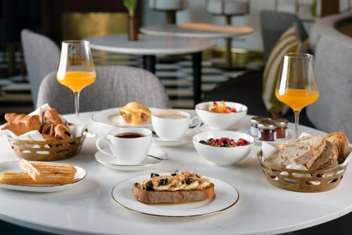 a table topped with plates of food and glasses of orange juice at Grand Hotel Centenari, Valencia, Autograph Collection in Valencia