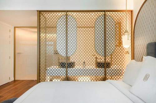 a bedroom with a white bed and a shower at Grand Hotel Centenari, Valencia, Autograph Collection in Valencia