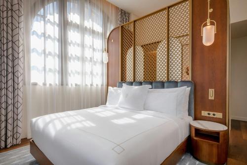 a bedroom with a large white bed and a window at Grand Hotel Centenari, Valencia, Autograph Collection in Valencia