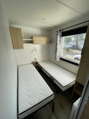 ein kleines Zimmer mit zwei Betten und einem Fenster in der Unterkunft Mobilhome in Saint-Jean-de-Monts
