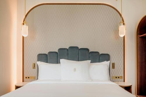 a bed with a blue headboard and white pillows at Grand Hotel Centenari, Valencia, Autograph Collection in Valencia