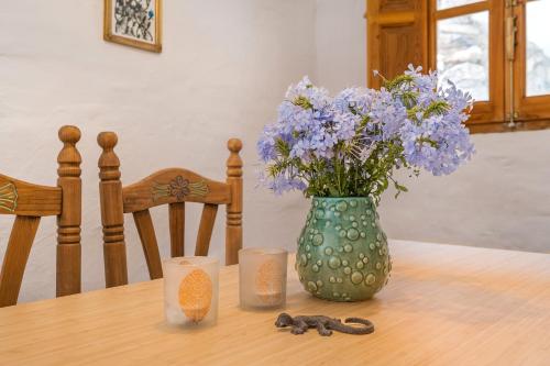 a vase with purple flowers and candles on a table at Off-Grid - Puerto Mika in Órgiva