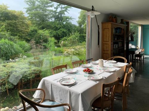 d'une table avec une nappe et des chaises blanches ainsi qu'une fenêtre dans l'établissement Maison Quatre Saisons, à Doudeville