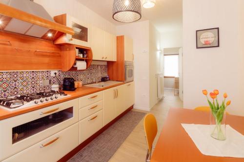 a kitchen with white cabinets and a table with a vase of flowers at Winding Village Suite in Trevi