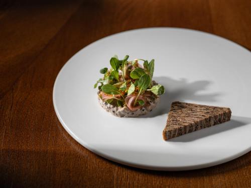 a white plate with a salad and a piece of bread at Platan Udvarhaz in Tata