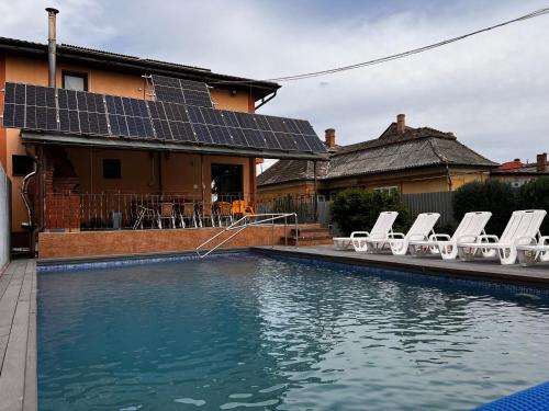 a pool with chairs and solar panels on a house at Vila Ovi Salin in Turda