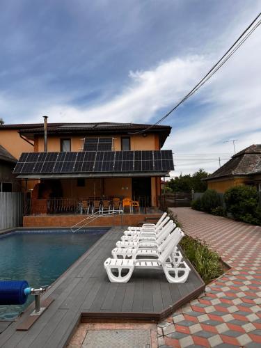 a group of white lounge chairs next to a pool at Vila Ovi Salin in Turda