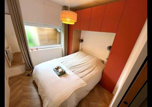 a small bedroom with a white bed with a red wall at Charmant T2 Tiny House Lumineux au Cœur de Jouy in Jouy-en-Josas