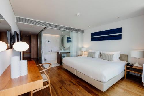 a bedroom with a large white bed and a bathroom at Troia Design Hotel in Troia