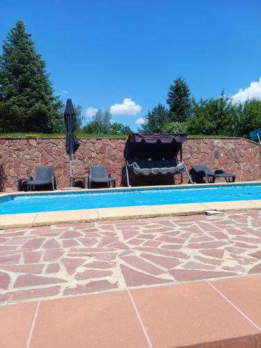 a pool with chairs and umbrellas next to a wall at Villa Villekulla in Chukovezer