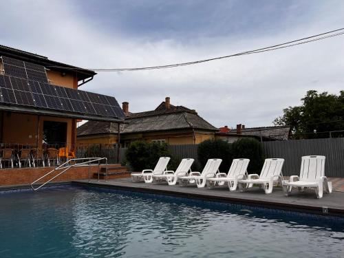 a group of white chairs sitting next to a pool at Vila Ovi Salin in Turda