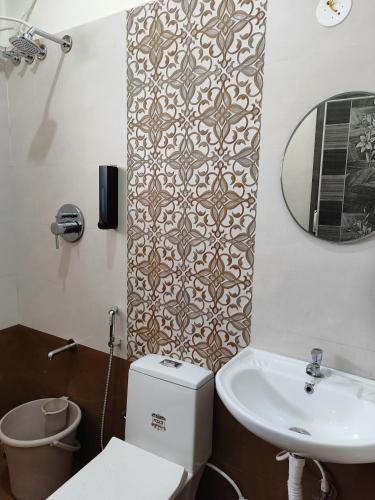 a bathroom with a toilet and a sink and a mirror at Samuels Comfort Homes in Bengaluru