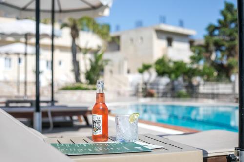 a bottle of beer sitting on a table next to a pool at Olevia Comfort in Faliraki