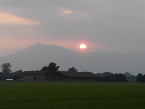 a sunset over a field with a barn and a mountain at La Locanda della Mandria in Venaria Reale