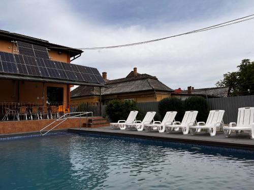 a group of white chairs sitting next to a pool at Vila Ovi Salin in Turda