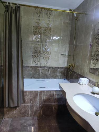a bathroom with a tub and a sink and a shower at Mansion Hotel in Stantsiya Kyzyl-Tukumachi