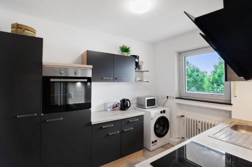 a kitchen with black cabinets and a washer and dryer at Bruchköbel 4 auch für Monteure in Bruchköbel