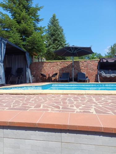 a pool with an umbrella and chairs and a table at Villa Villekulla in Chukovezer