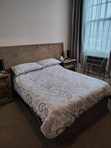 a bed in a bedroom with two tables and a window at The Wheatsheaf in Salisbury