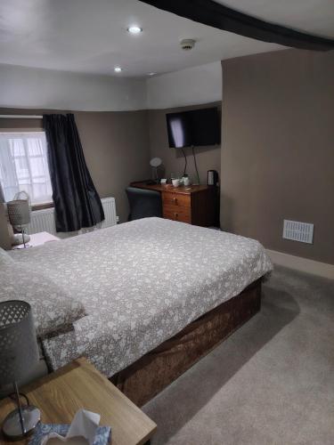 a bedroom with a bed and a flat screen tv at The Wheatsheaf in Salisbury