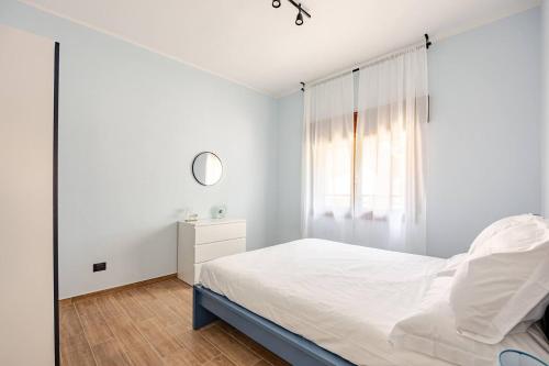 a white bedroom with a bed and a window at Appartamento del Paradosso in Spilamberto