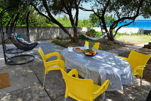 a table with yellow chairs and a table with a mirror at House Ana in Banj