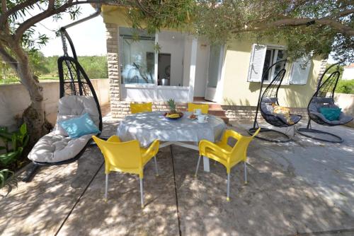 a table and yellow chairs and a table and a table and chairs at House Ana in Banj