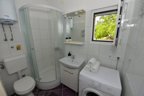 a white bathroom with a sink and a toilet and a shower at House Ana in Banj
