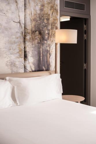 a bedroom with a white bed and a painting at Dolce by Wyndham Versailles - Domaine du Montcel in Jouy-en-Josas