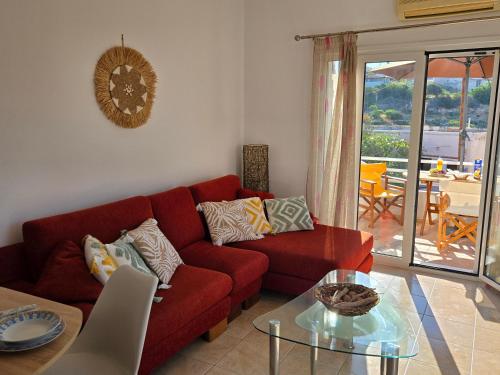a living room with a red couch and a glass table at Nora Apartment in Almyrida in Chania Town