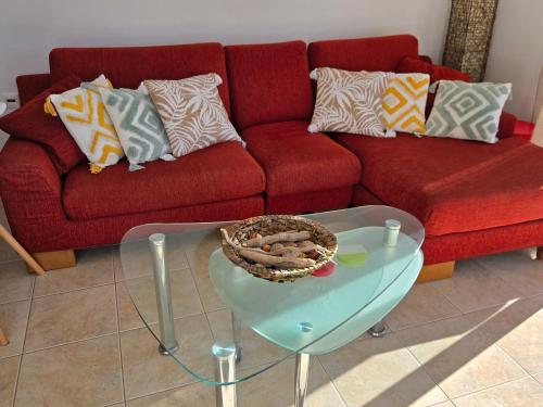 a living room with a red couch and a glass table at Nora Apartment in Almyrida in Chania Town