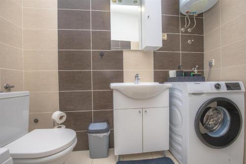 a bathroom with a toilet sink and a washing machine at House Matilda in Primošten