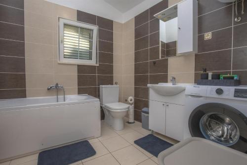a bathroom with a toilet sink and a washing machine at House Matilda in Primošten