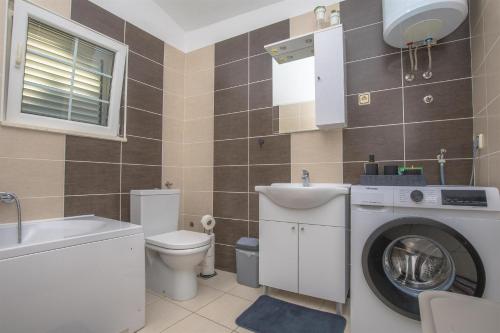 a bathroom with a washing machine and a toilet at House Matilda in Primošten