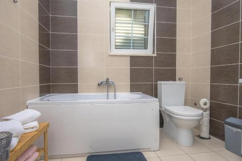 a bathroom with a tub and a toilet and a window at House Matilda in Primošten