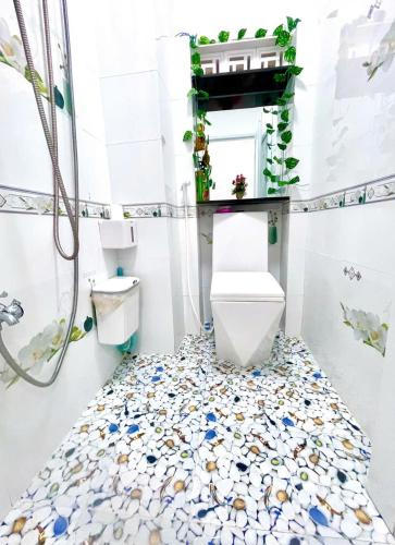 a bathroom with a toilet and a floor covered in rocks at Hoàng Nga 2 Homestay in Phan Thiet