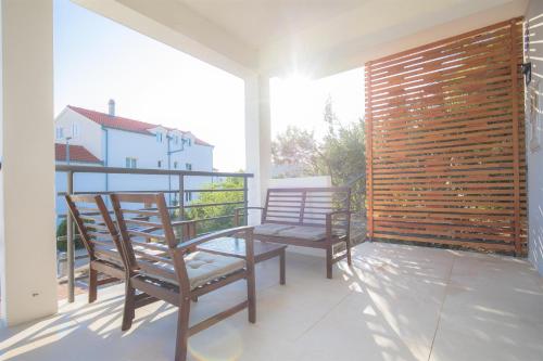 a balcony with two chairs and a wooden wall at House Matilda in Primošten