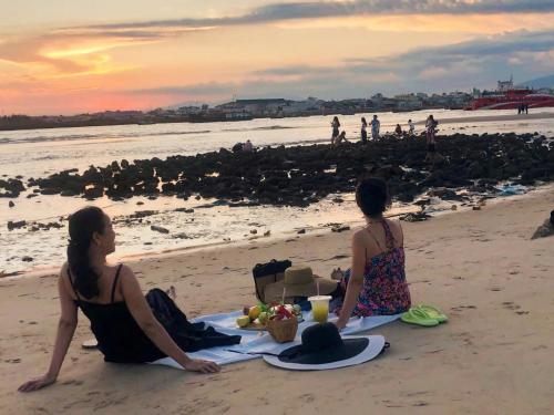 two women sitting on the beach with a table of food at Hoàng Nga 2 Homestay in Phan Thiet