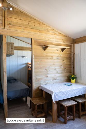 une chambre avec une table et des bancs dans une cabine dans l'établissement Camping Routes du Monde ATC La Hume-Arcachon, à Gujan-Mestras
