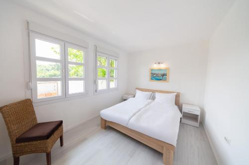 a white bedroom with a bed and a chair at Holiday Home Soul 