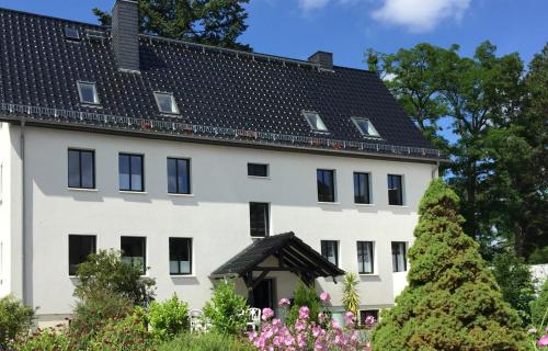 a large white building with a black roof at Haus am Röblinsee - Ferienwohnungen in Fürstenberg in Fürstenberg-Havel