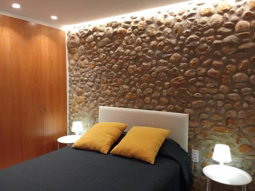 a bedroom with a bed with a stone wall at L'horitzó II in Llado