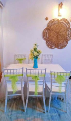a white table with two chairs and a vase of flowers at Hoàng Nga 2 Homestay in Phan Thiet