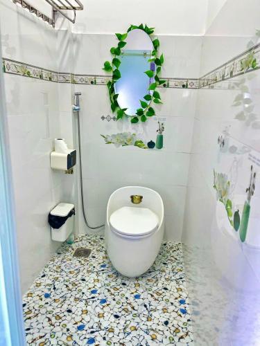 a white bathroom with a toilet and a mirror at Hoàng Nga 2 Homestay in Phan Thiet