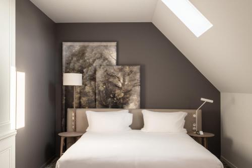 a bedroom with a bed with a painting on the wall at Dolce by Wyndham Versailles - Domaine du Montcel in Jouy-en-Josas