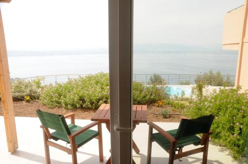 a patio with a table and chairs and a view of the ocean at Aegean View Villa in Loutraki