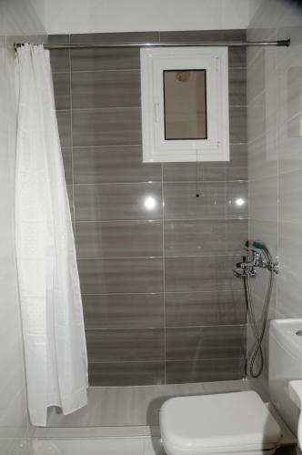 a bathroom with a shower curtain and a toilet at Aegean View Villa in Loutraki